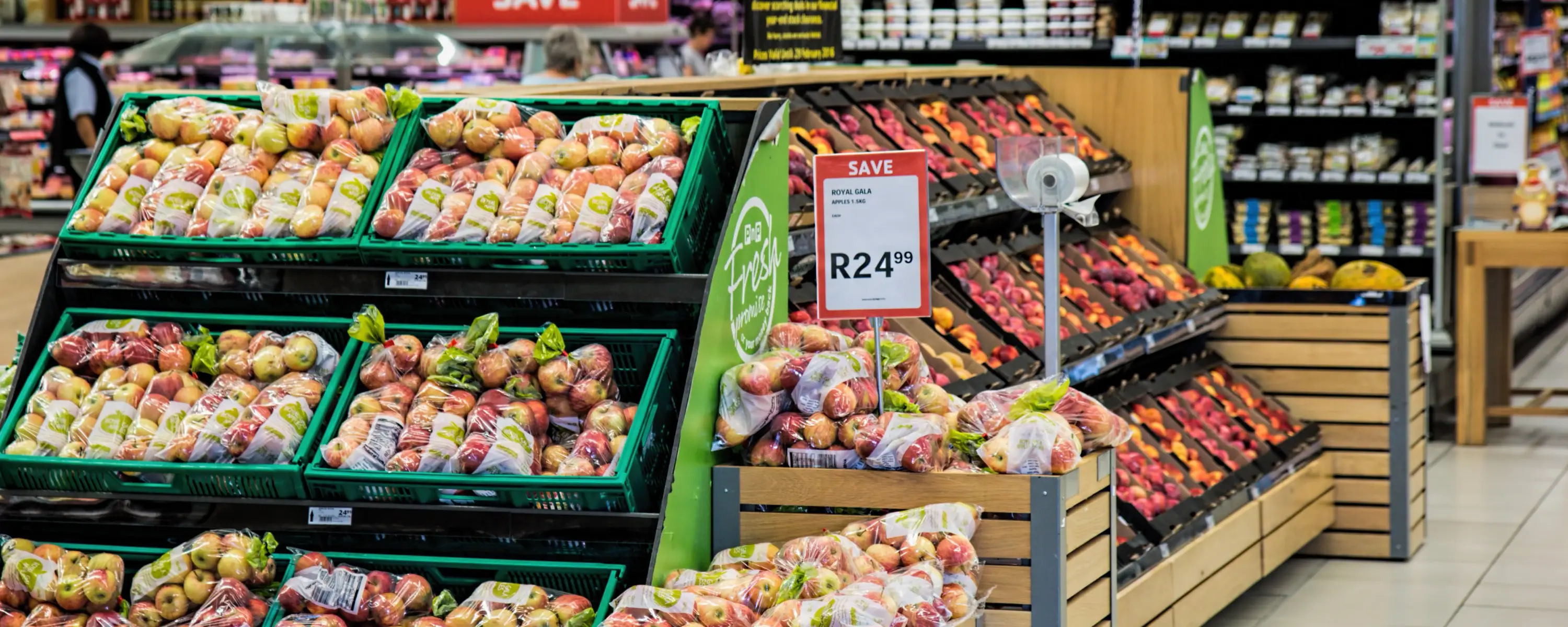Display of fresh peaches in green crates with a price sign.