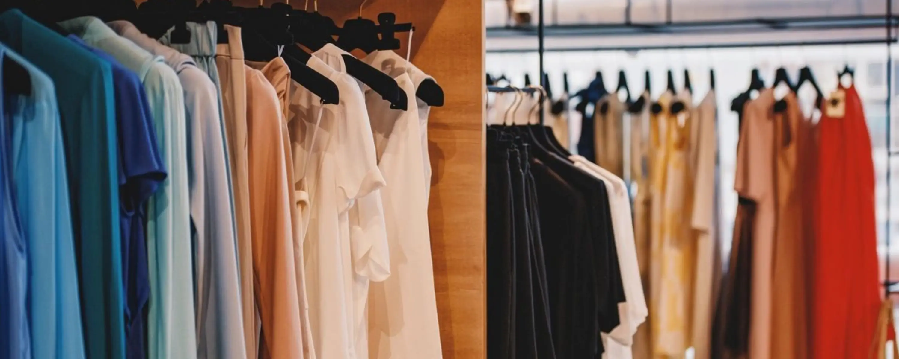 Clothing rack with white and black garments hanging on wooden hangers.